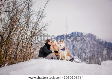 Sweet blonde with her boyfriend and dog sitting on a snowy mountain