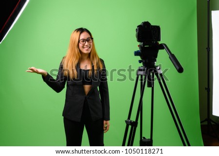Studio shot of young Asian businesswoman against green background