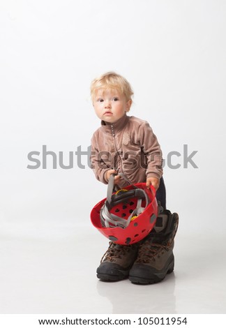 Little girl in big boots and helmet in hands