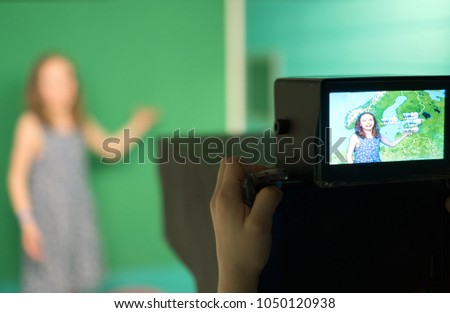 Weather forecast. Little girl standing in front of camera on green screen.