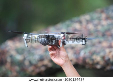 Hand with drone flying during the day in field.