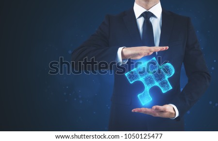 Man holding glowing blue puzzle on blurry background. Future and innovation concept 