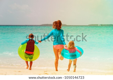 happy mother with son and daughter run have fun on beach