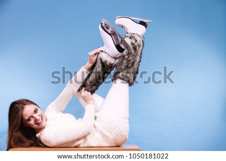 Woman wearing skates fur warm socks. Girl getting ready for ice skating. Winter sport activity. Studio shot on blue