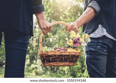 Couple in love walking and holding a picnic basket on nature outdoor background.