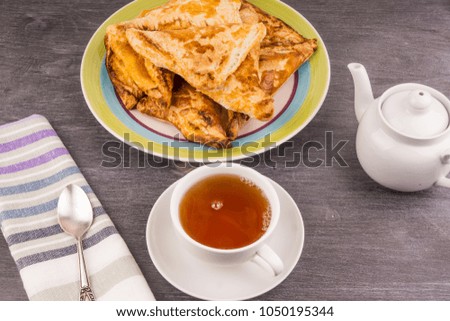 Delicious golden triangles of puff pastry on the table and a cup of tea - top view