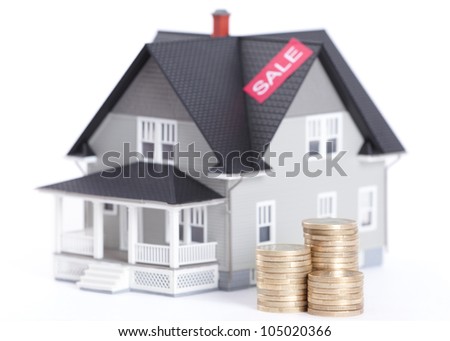 Realty concept - stacks of coins in front of house architectural model, isolated