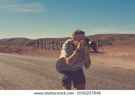 A tourist with a camera on the road in the desert photographs