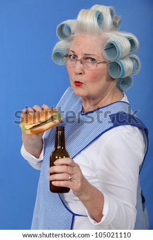 funny picture of grandma with hair curlers relishing cheeseburger with beer