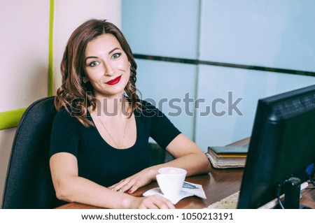 Young beautiful girl sits in the office at the computer table