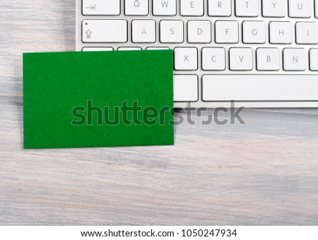 Business card in green color on computer keyboard. Mockup.