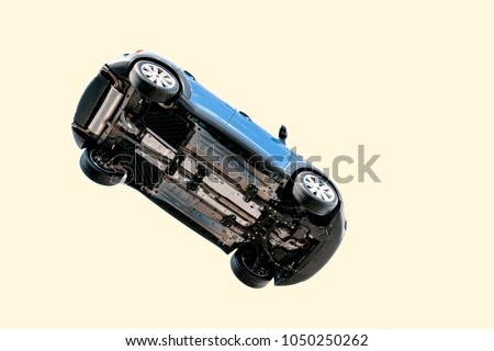 A car flying through the air (in the pale blue sky) with the underside including, wheels, engine and exhaust pipe visible Royalty-Free Stock Photo #1050250262