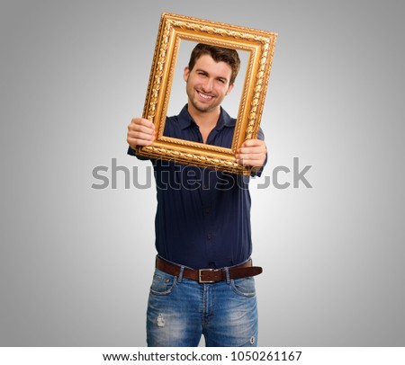Young Man Holding Picture Frame Isolated On Grey Background