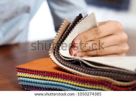 Sampler of fabric colors. The woman watches the colors and patterns of upholstery fabrics. Royalty-Free Stock Photo #1050274385