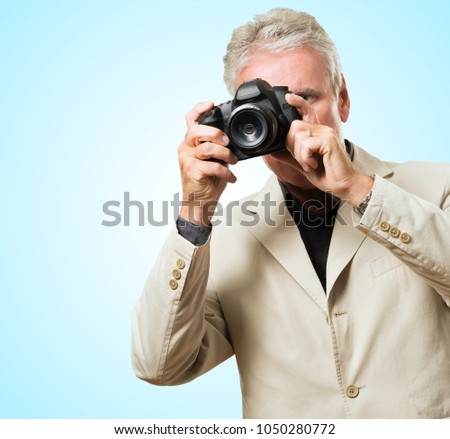 Mature Man Capturing Photo against a blue background