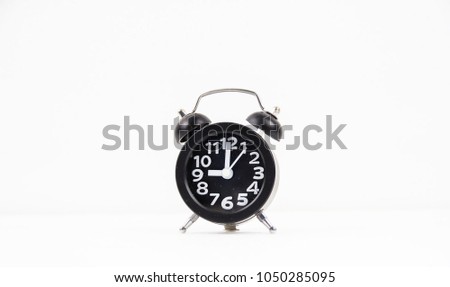 Closeup the black alarm clock with white number put on white background.it's nine o'clock on the dial,blurry light around.