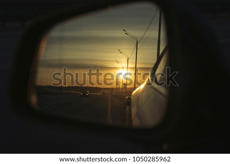 Sunrise on highway road in left side view mirror driver. Focus on reflection in smaller mirror. Close up photo of left side view mirror