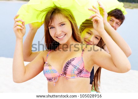 Portrait of happy teenage girl carrying mattress with her friends helping her