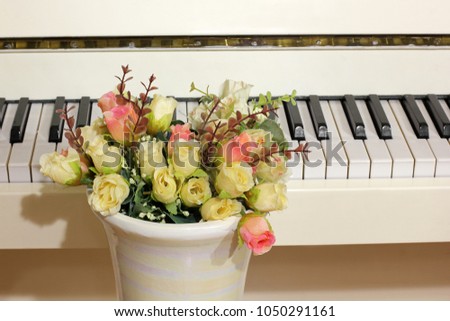 Vase with flowers and piano. Roses and musical instrument