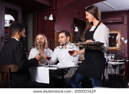 Portrait of chatting 25s adults in restaurant and cheerful waitress