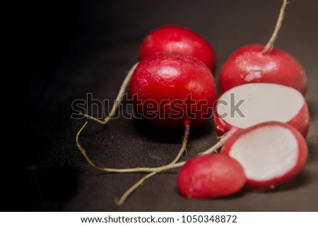 Low lighting photo of red radishes against a black background