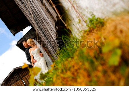 Beautiful wedding couple posing on green fiel near old house