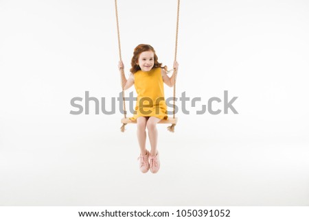 Little stylish child in dress riding on swing isolated on white Royalty-Free Stock Photo #1050391052