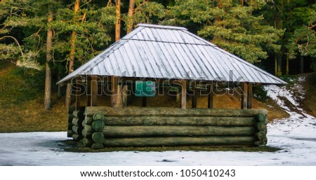 Snow Covered Wooden Gazebo in a Cloudy Winter Day. Translation of text in photo - "Certenes Mound"