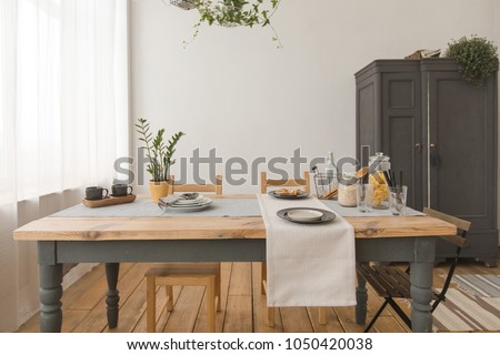 dining wooden table and chairs in modern home with elegant table setting Royalty-Free Stock Photo #1050420038