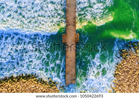 Aerial view over the old broken bridge in the sea, sunrise shot