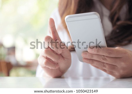 Closeup image of a woman holding , using and looking at smart phone 