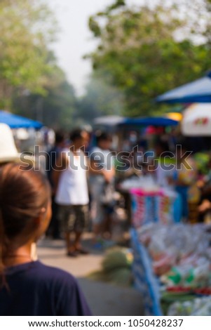 Blurry image of a group people shopping at a flea market in the country.