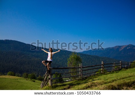 Woman with hands up on top of mountains with blue sky. Woman enjoying free happiness in beautiful landscape. Travel concept