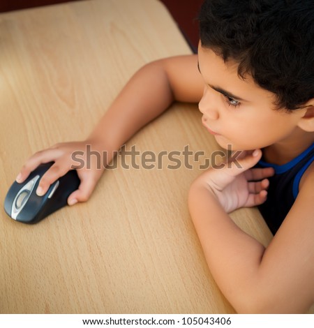 Cute hispanic boy working with a computer on his bedroom at night (pictured from above)