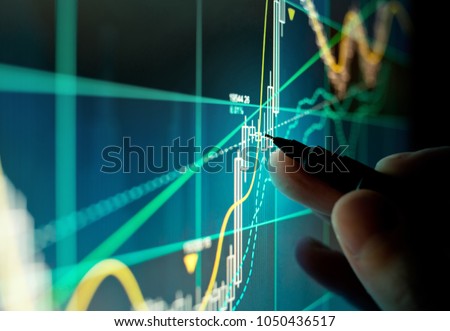 A stock trader checking technical markers of a stock on a computer screen. Royalty-Free Stock Photo #1050436517