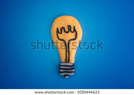 Light bulb made out of play clay on blue background. Idea concept. Close up.