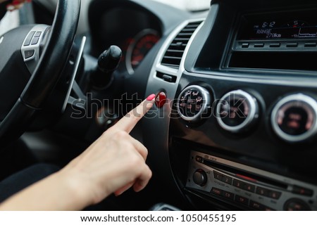 Woman finger pressing emergency button on car dashboard