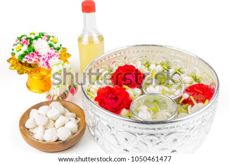 Floating jasmines and roses in silver Thai style dippers, white clay filler, scented water and a garland isolated on white background