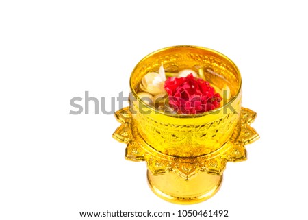A thai traditional golden cup or small dippers with floating jusmine and a damask rose isolated on white background