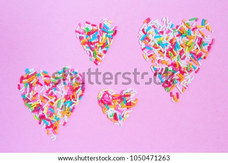Heart from multi-colored confetti on a pink background flat  lay layout from above