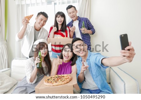 young people eat pizza and selfie happily with party