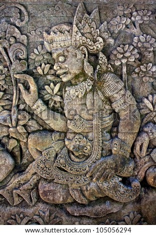 Oriental background. Bas-relief with a man  surrounded by floral ornament. From a balinese temple