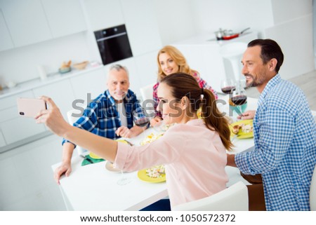 Beautiful, attractive, cheerful women shooting self portrait on smart phone with her relatives, guests, visitors in house, apartment, room, couples sitting at the table, eating food, drinking wine