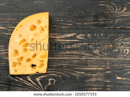 Piece of cheese with holes on a blank wooden background, top view