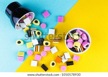 top view of colorful liquorice allsorts spilling from a cup Royalty-Free Stock Photo #1050578930