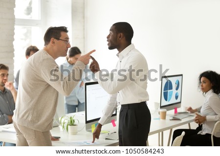 Multiracial african and caucasian colleagues disputing having disagreement at work blaming each other in mistake, diverse coworkers arguing about project, having conflict fight at workplace concept Royalty-Free Stock Photo #1050584243
