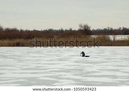 A fisherman on the ice. Winter fishing.  Winter landscape of the lake and the fisherman.