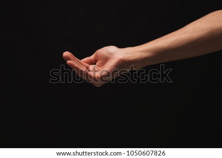 Holding, asking or offering. Outstretched male hand, man keeping empty palm on black isolated background