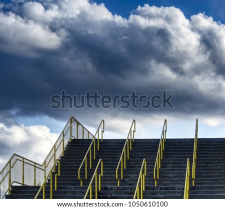 Concrete stairway with bright yellow railings. Partly cloudy sky in background. Image contrast enhanced by digital tone mapping.