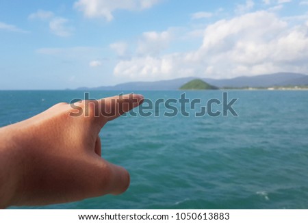 Photo of hand pointing finger into distance of sea coast, cloudy sky